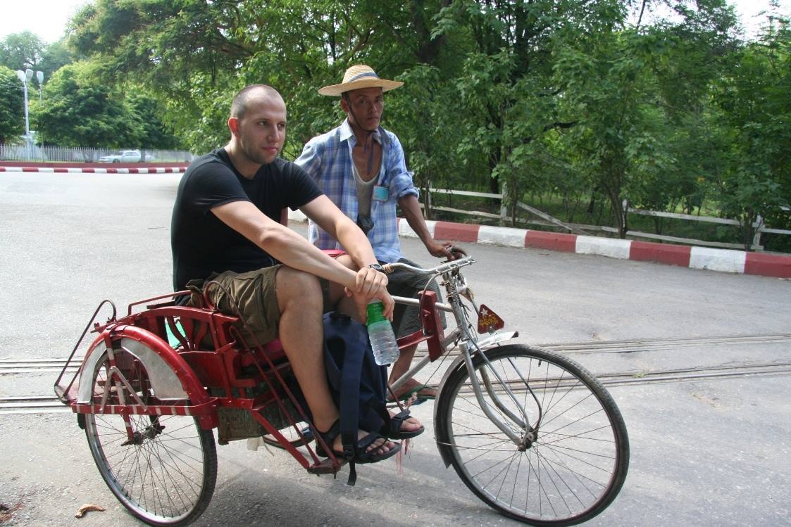 Turista su risciò a triciclo rosso con conducente che pedala