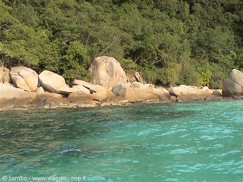 Turquoise water beside pale granite boulders and tropical forest on the coast