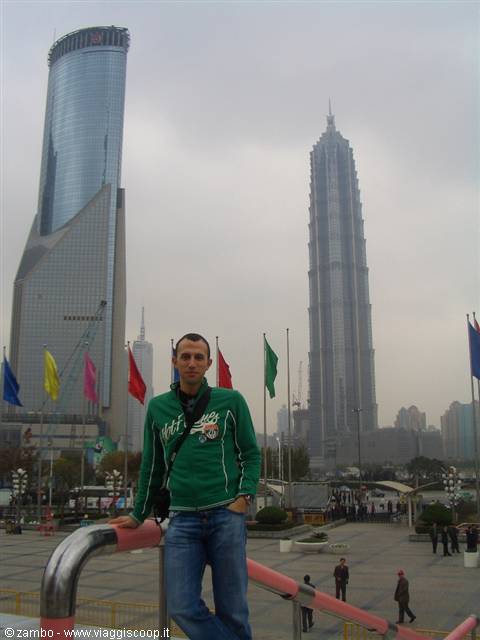 Tourist in green sweatshirt leaning on a railing in front of Pudong towers, Shanghai