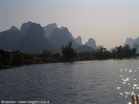 Limestone karst peaks reflected on the Li River, hazy light sparkling on water