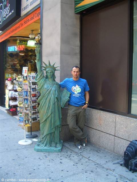 Tourist leaning on a small Statue of Liberty replica outside a souvenir shop