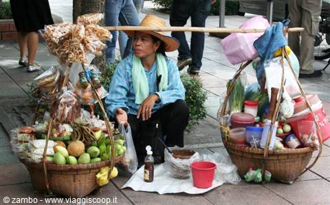 Street vendor with fruit baskets hanging from a shoulder pole, Bangkok