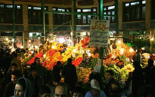 Covered bazaar in Tehran, crowded fruit and vegetable stalls under light bulbs