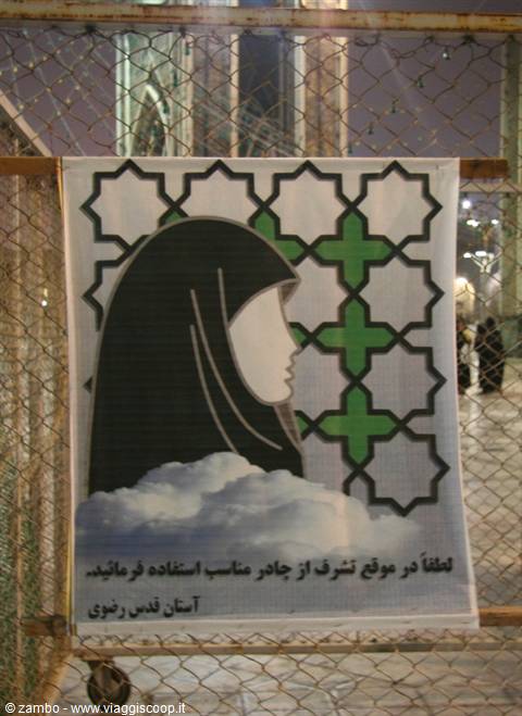 Poster with veiled face hung on wire fence, lit at night, Mashad