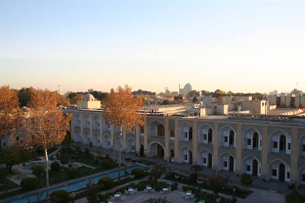 Brick arches courtyard with pools and autumn trees, dome in background, Esfahan