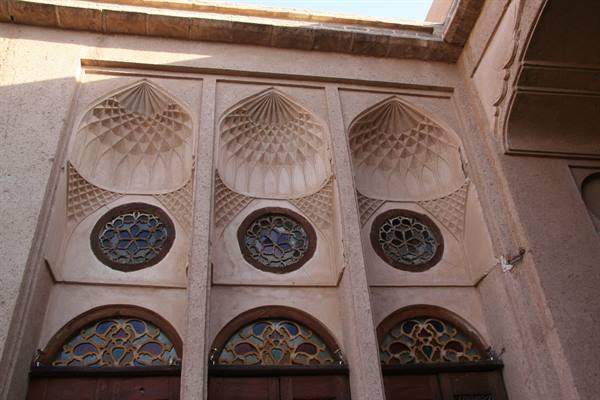 Stucco facade with muqarnas and round stained glass windows, Yazd
