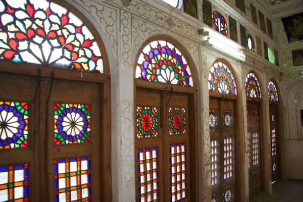 Wooden doors with colorful stained glass and carved plaster, Persian historic house in Yazd