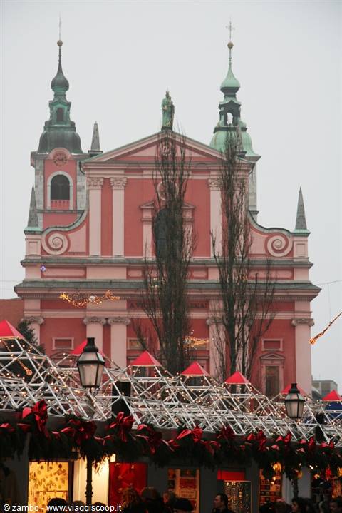 Pink Franciscan church behind Ljubljana's Christmas market stalls in winter