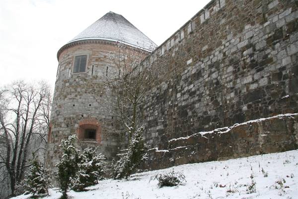 Round stone tower and snowy castle walls on a winter day
