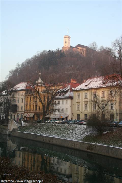 Ljubljana Castle on the hill above snow-dusted buildings and the Ljubljanica river
