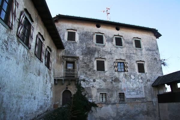Castle inner courtyard with faded frescoed facade and wrought iron balcony