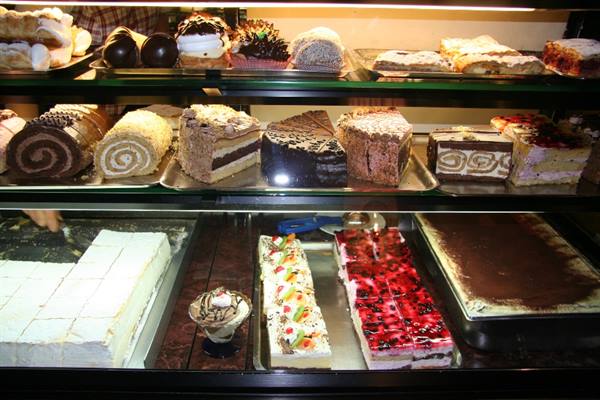 Bakery display case with layered cakes, chocolate rolls and fresh desserts