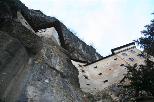 Predjama Castle built into the limestone cliff under a cloudy sky