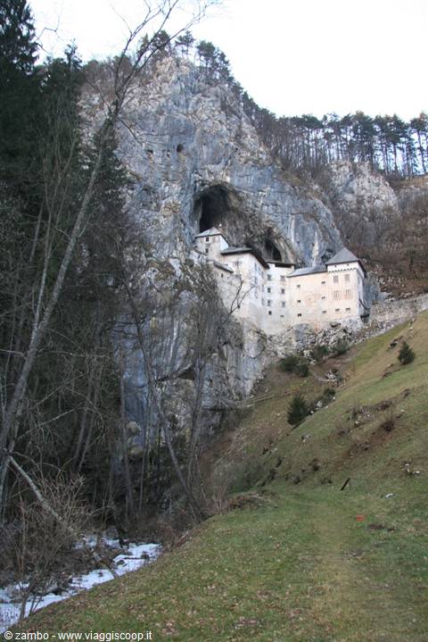 Predjama Castle built into the limestone cliff above the wooded slope
