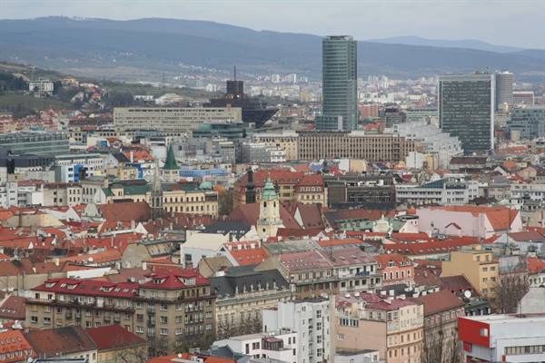 Red rooftops of Bratislava with skyscrapers and hills under grey sky