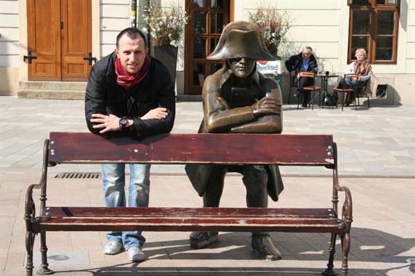 Tourist leaning on the bench next to a bronze soldier statue
