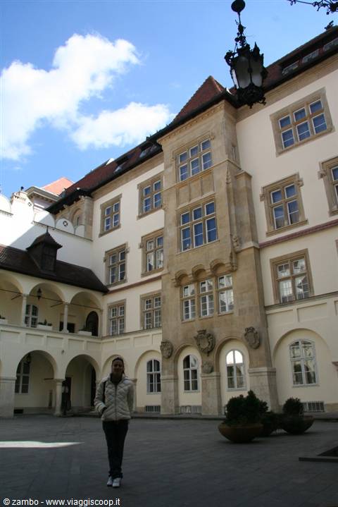Girl walking in a Renaissance arcaded courtyard, pale stone facade, wrought-iron lantern