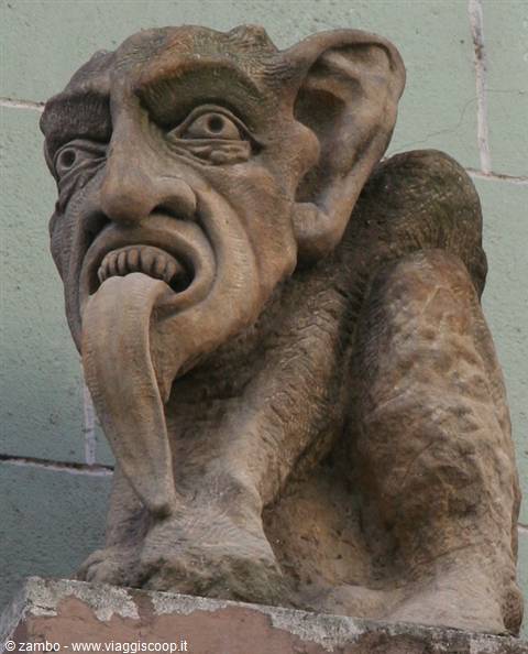 Stone gargoyle sticking out its tongue against a pale green wall