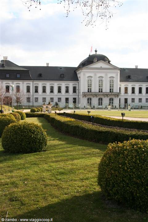 White baroque palace with dome, geometric hedges and shrubs in the park, Gödöllő