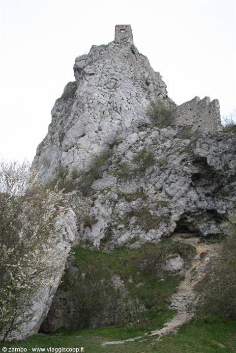 Stone castle tower atop a rocky crag, ruined walls, overcast sky