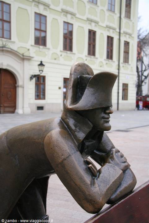 Bronze statue of a Napoleonic soldier sitting on a bench in a square