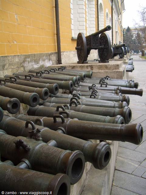 Old bronze cannons lined up beside a yellow facade at the Kremlin Arsenal in Moscow
