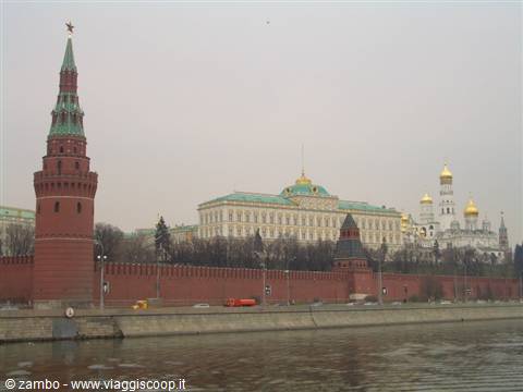 Red Kremlin walls and tower in Moscow along the river, grey sky