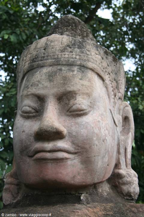 Carved stone Khmer deity head among the trees of Angkor