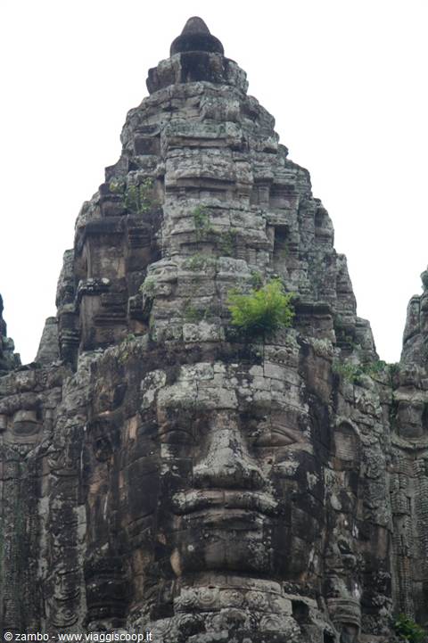 Carved stone face on a Bayon temple tower, grey stones and moss