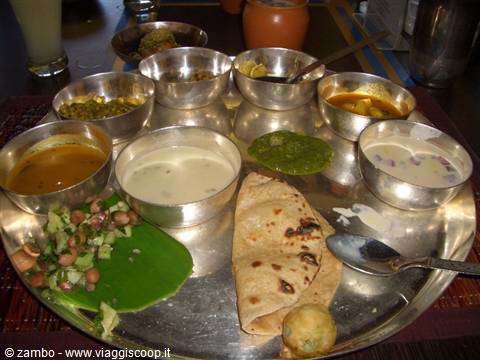 Indian thali on steel tray with small bowls of dal, chutney and roti