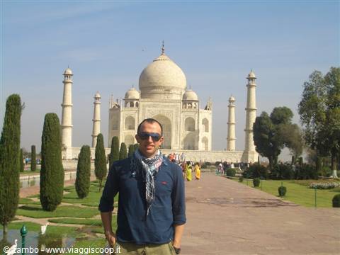 Tourist with scarf in front of the white marble Taj Mahal, sunny gardens