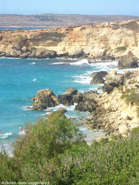 Yellow limestone cliffs over turquoise water, swimmers among the rocks in Malta