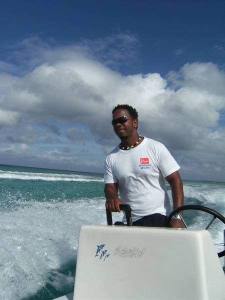 Man in sunglasses steering a white speedboat through turquoise waves