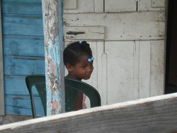 Smiling girl on green plastic chair in front of wooden house
