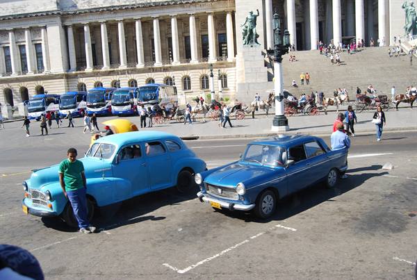 Vintage blue cars in front of Havana's Capitolio, tourists and horse carriages