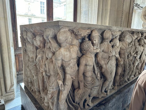 In front of an ancient Roman sarcophagus at the Louvre, timeless wonder.