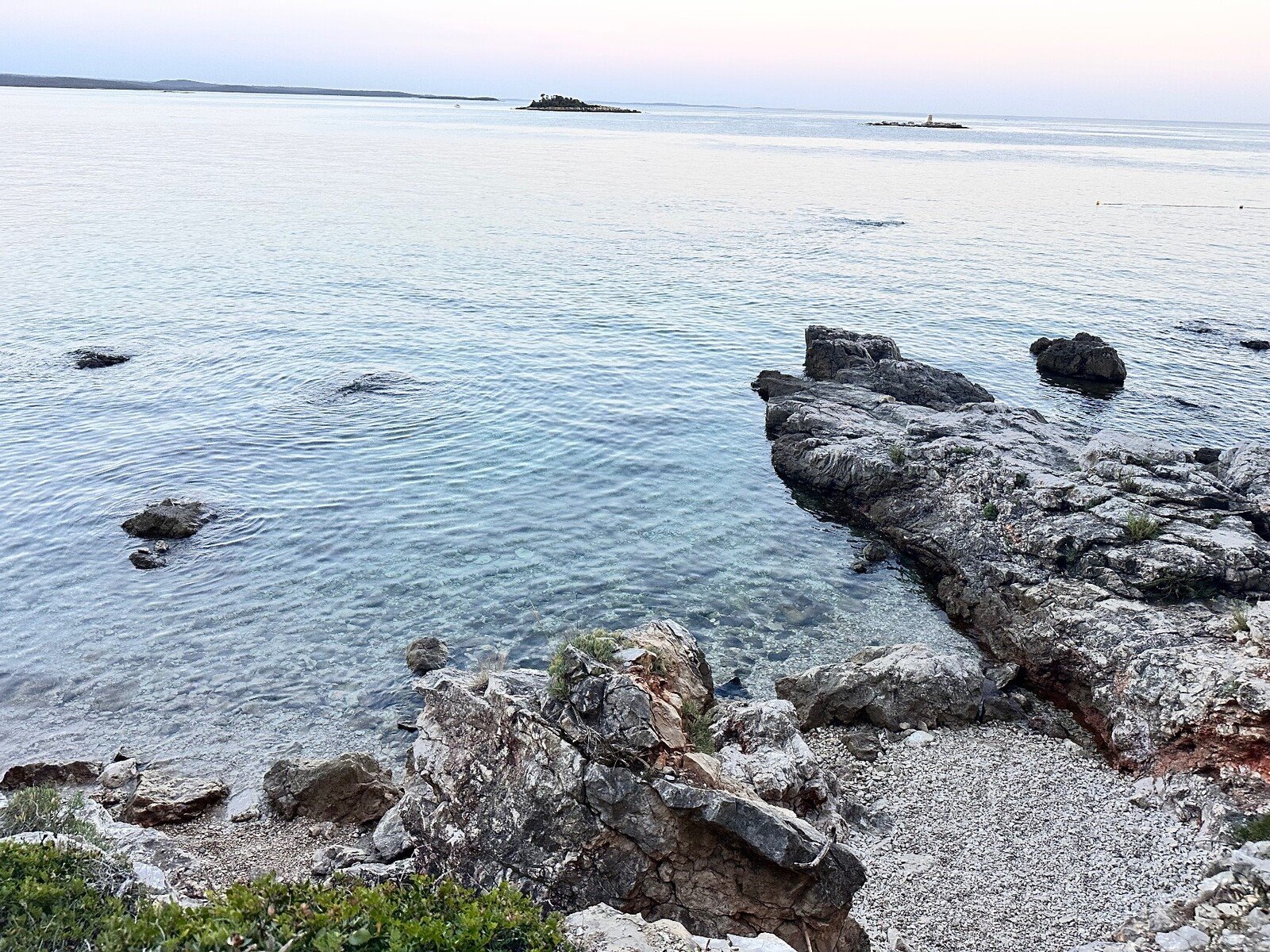 A quiet sunset over the crystal-clear sea among the rocks, a suspended moment.