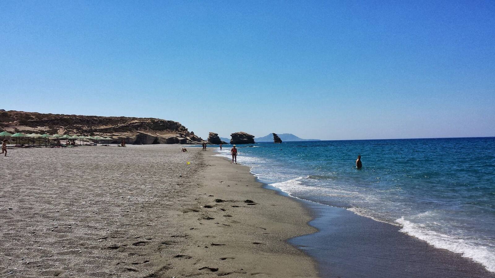 Passeggiata silenziosa sulla spiaggia di Vlychada, tra sabbia scura e onde.