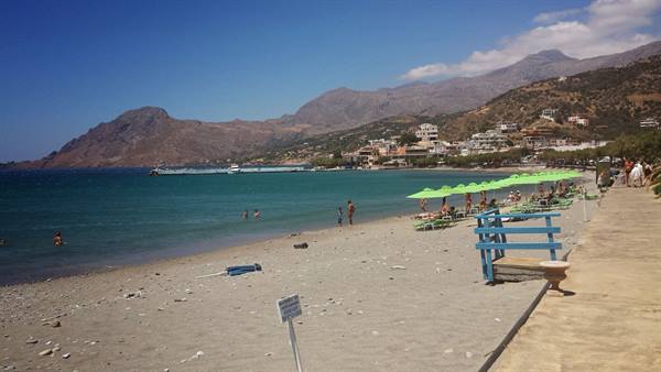 A lazy day among green umbrellas and turquoise sea, under the mountains.
