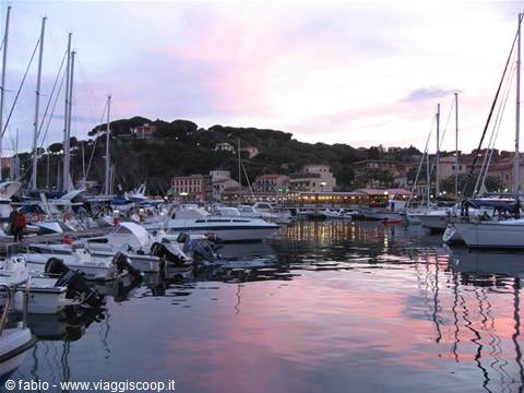 Sailboats moored in the marina at dusk, pink sky reflected on the water