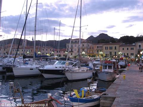 Sailboats moored at the harbor, colorful buildings and hills at dusk behind