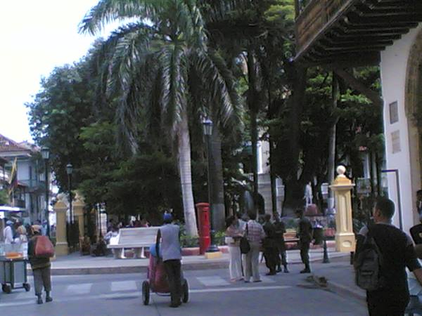 Colonial square with palm trees, white benches and people in daylight