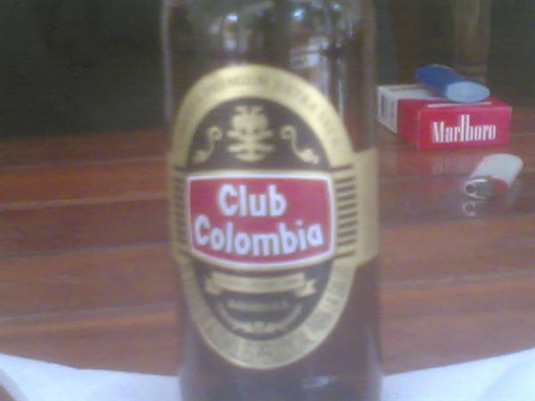 Club Colombia beer bottle on wooden table with Marlboro pack