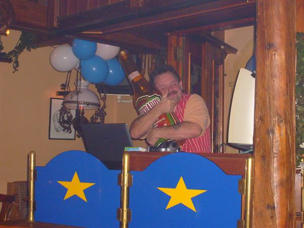 Man at a bar hugging a giant Hoegaarden bottle among balloons