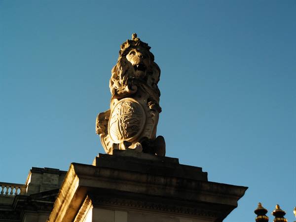 Stone lion sculpture with royal crest at Buckingham Palace in golden light