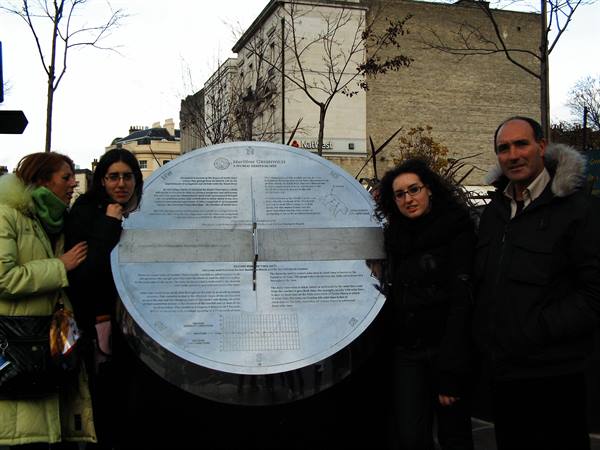 Four people standing beside the metallic Greenwich Meridian marker disc