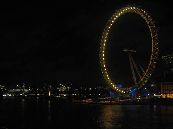 The illuminated London Eye at night reflects on the Thames waters