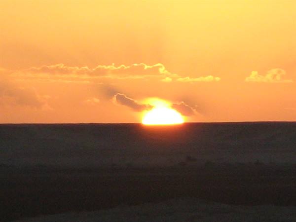 Low sun touching the sea under orange clouds