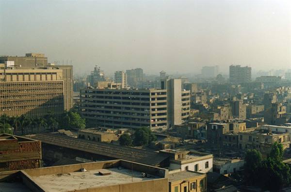 Concrete buildings hazy in morning light above flat brick rooftops