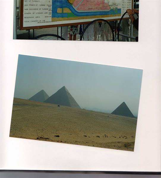 The three Giza pyramids in haze, sand and pale light